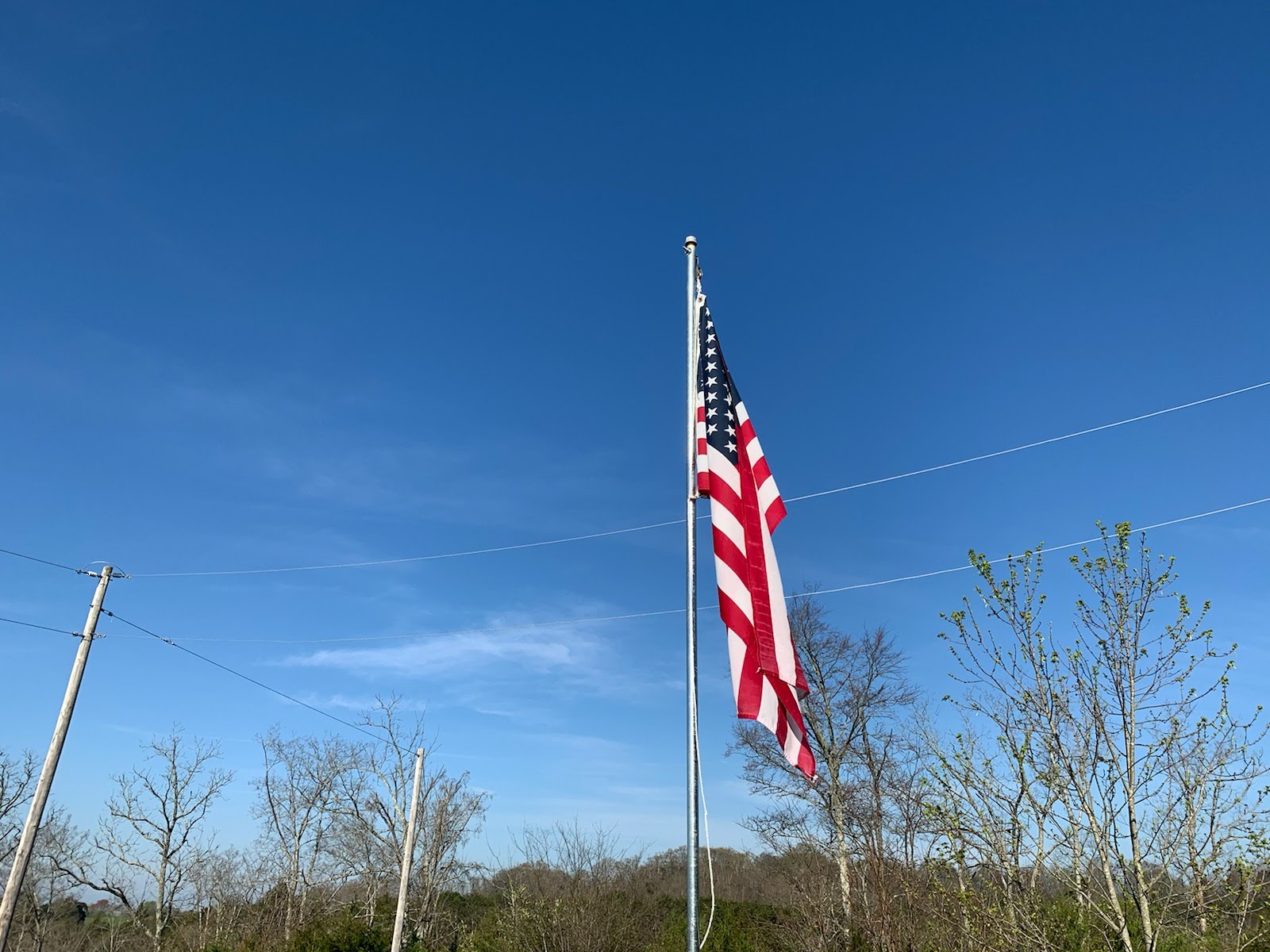An American flag on flag post with bluse sky back drop